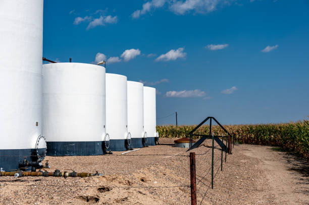 crude oil storage tanks with secondary containment and fencing in a rural corn field. High quality photo